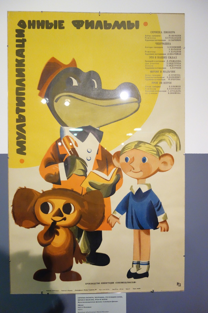На плакате перечислены мультфильмы: «Скрипка пионера», «Чебурашка», «Это в наших силах», «Мячик и мальчик», «Урок не впрок». Изображены Чебурашка, крокодил Гена и пионерка.